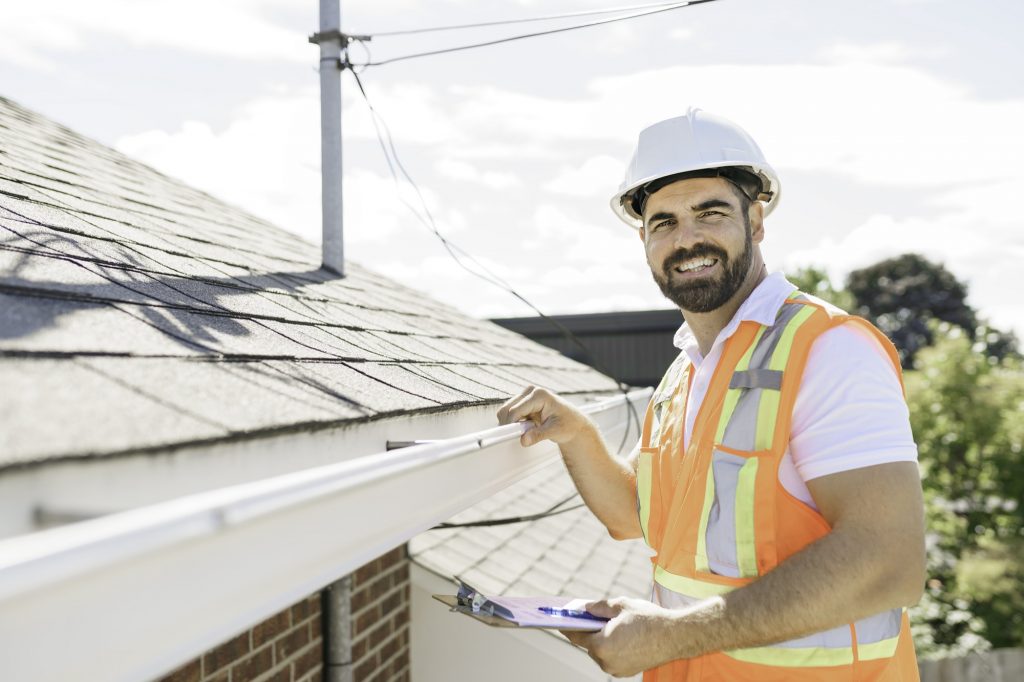 Man inspecting gutters on a residential house